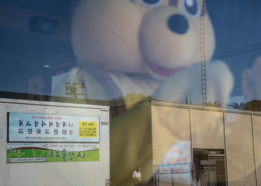 A storefront window reflects banners catering to Koreran speakers from across the street near 1st Street and Western Avenue 