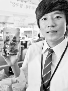 Oh Changhee, an economics student from Jin Ju, South Korea at the 40th annual Korean Festival in Koreatown. He is part of a program that incubates students to become experts on trading. He and his friends traveled to Los Angeles to practice sales in a foreign environment. His entrepreneurship program lasts three months where afterwards, he is expected to travel to other countries to participate in exhibits to share what he learned. He is holding a dry radish soup he and his two colleagues are selling at their table.