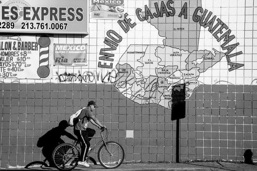 A large mural showing a map of Central America alongside advertisements aimed toward Mexican Americans are displayed on the building of a barber shop on the corner of Edgemont Street and Beverly Boulevard. 